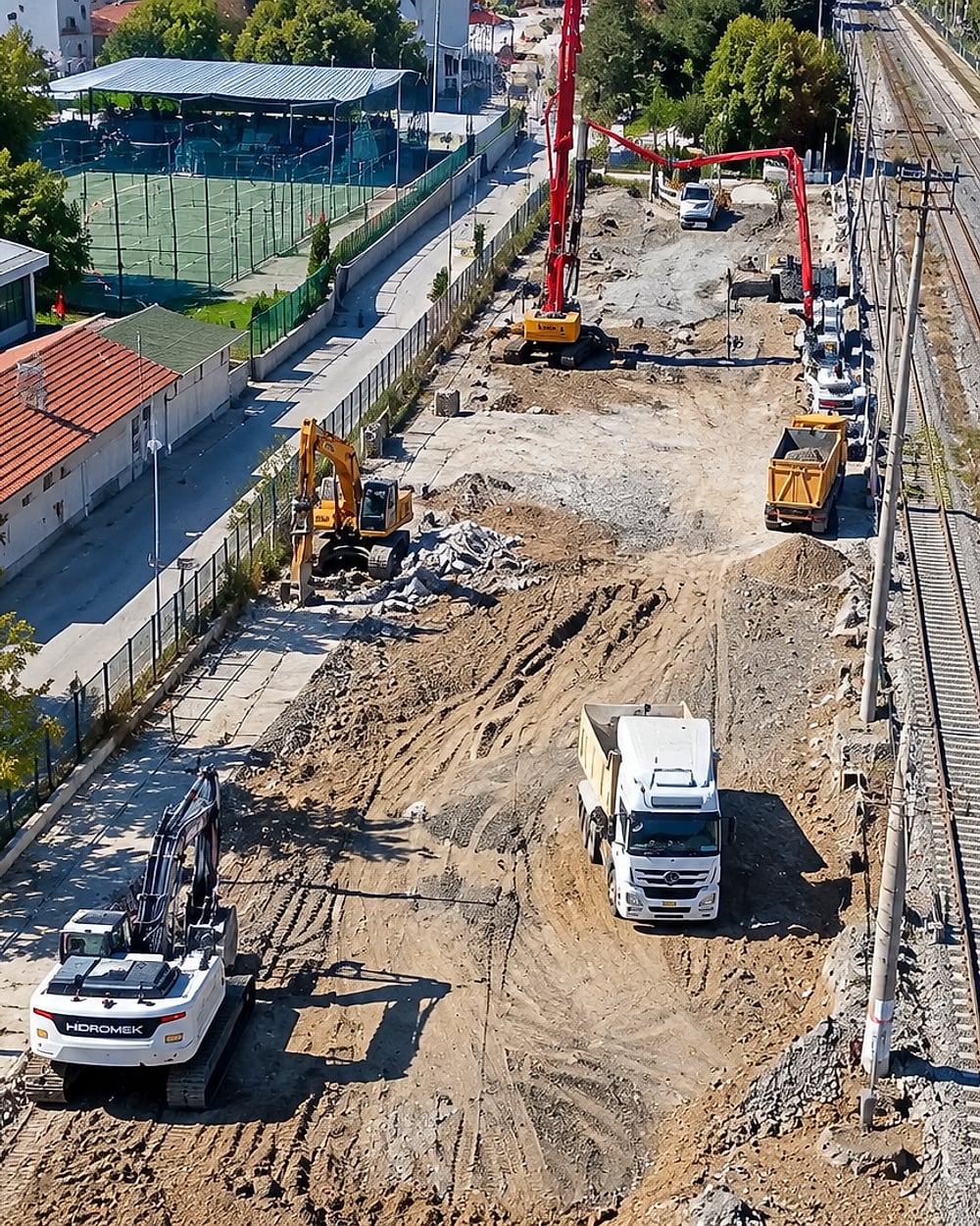 Demiryolu hattı yanındaki şantiyede çalışan iş makineleri ve kamyonların havadan görünümü