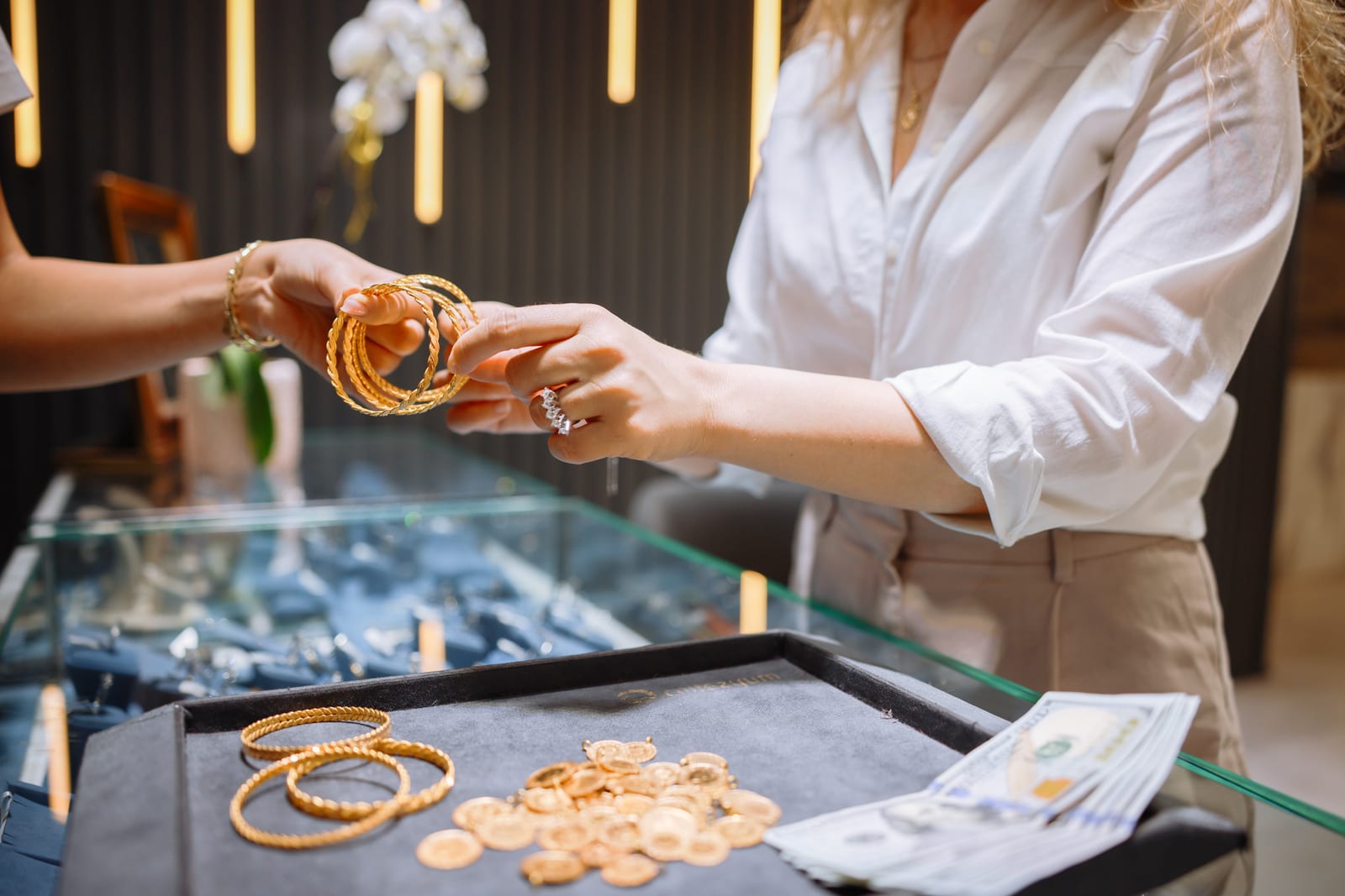 Sales advisor showing gold bangles to a customer at a jeweller's counter